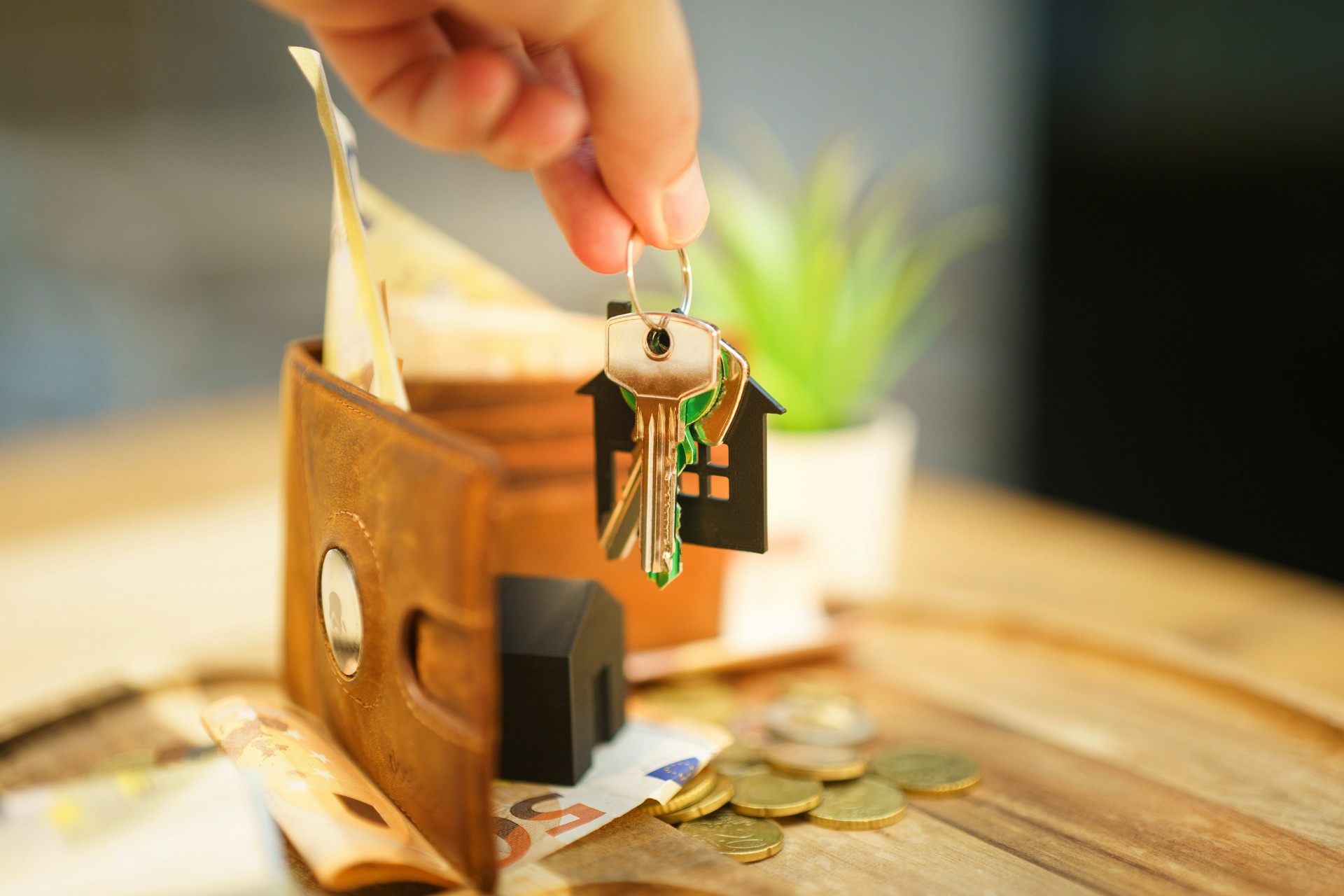 House keys held over a wallet with euro banknotes and coins